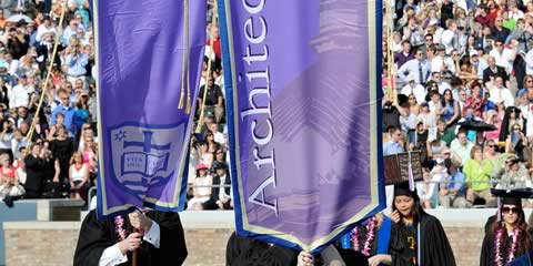 Students carry two purple banners in a procession: one bearing the Academic Seal and the other beariing the word Architecture