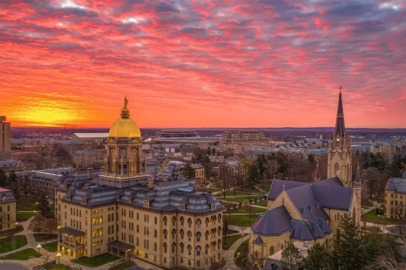 An orange and pink sunrise over the Golden Dome and Basilica spire.