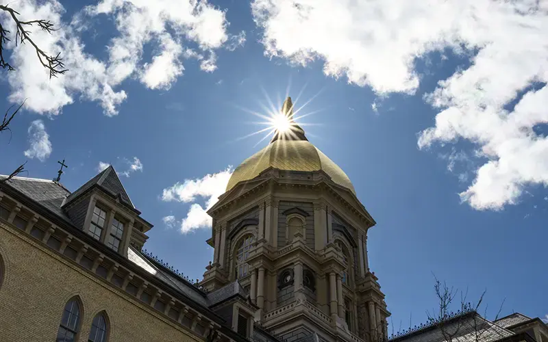 The sun shining behind the Golden Dome.