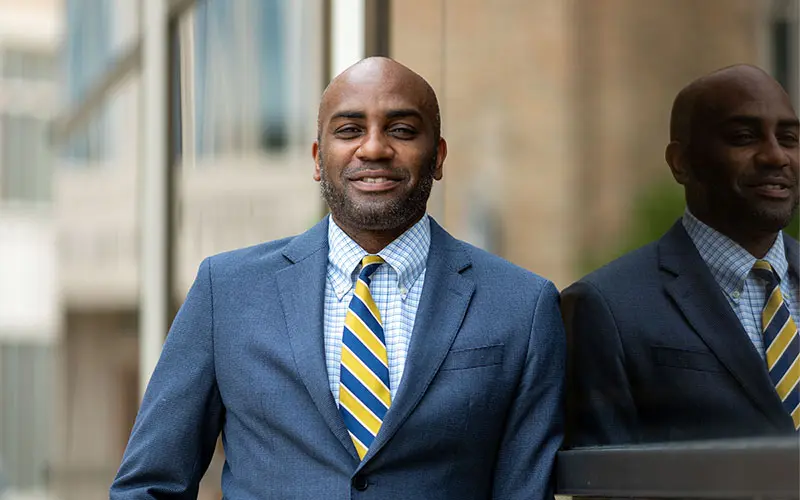 Ernest Morrell stands against a relfective building.