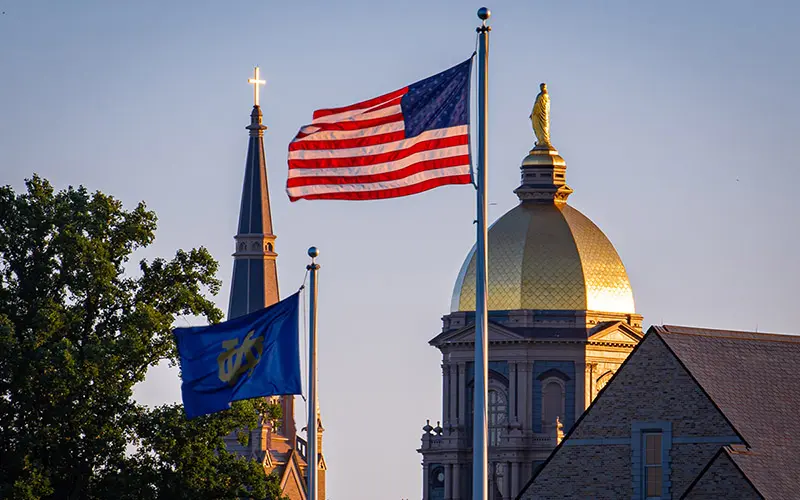 The Notre Dame and U.S. flags fly in front of the campus skyline