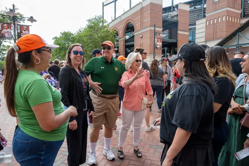 Several teachers and Claire Roach stand with donors Joe and Marcia Croteau outside the gate to Camden Yard. 