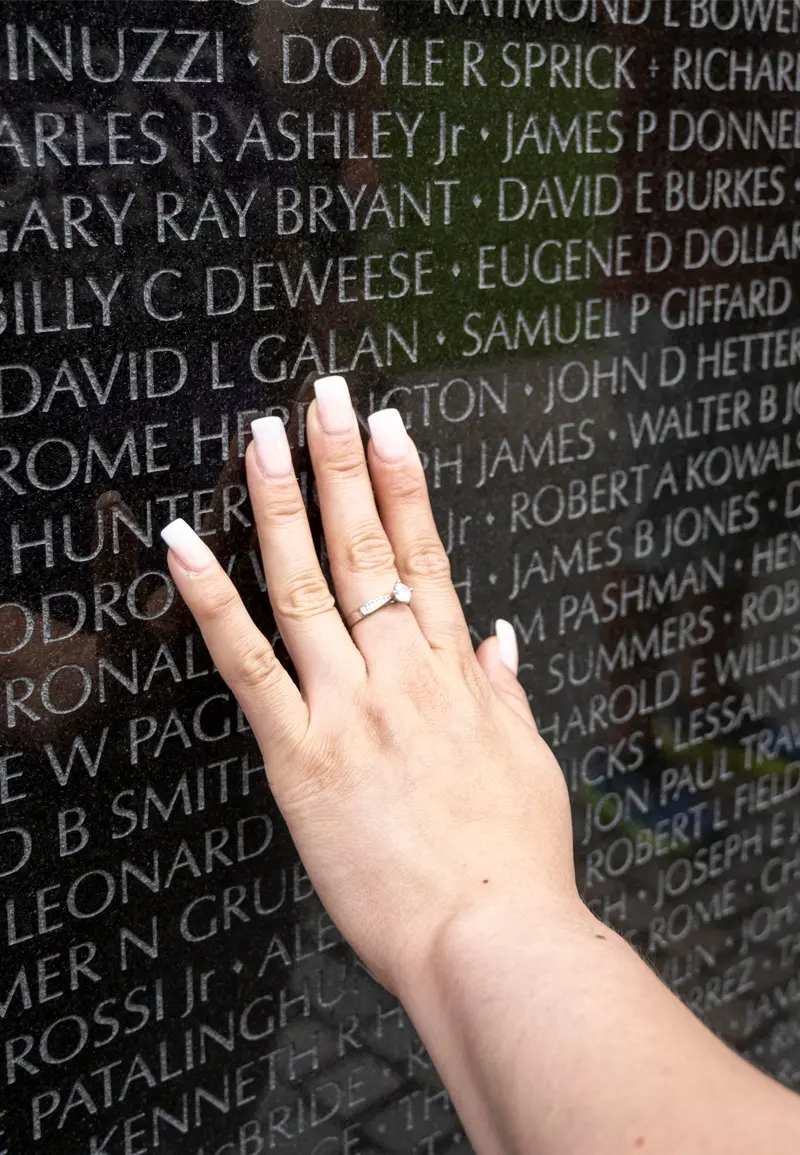 A close up of a hand touching the Vietname War Memorial.