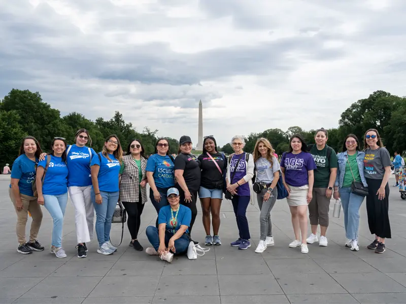 A group of teachers pose for a picture with the Washington Monument in the background.