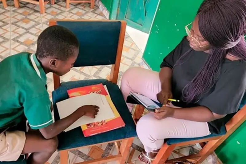 A woman sits with a young boy working through homework.