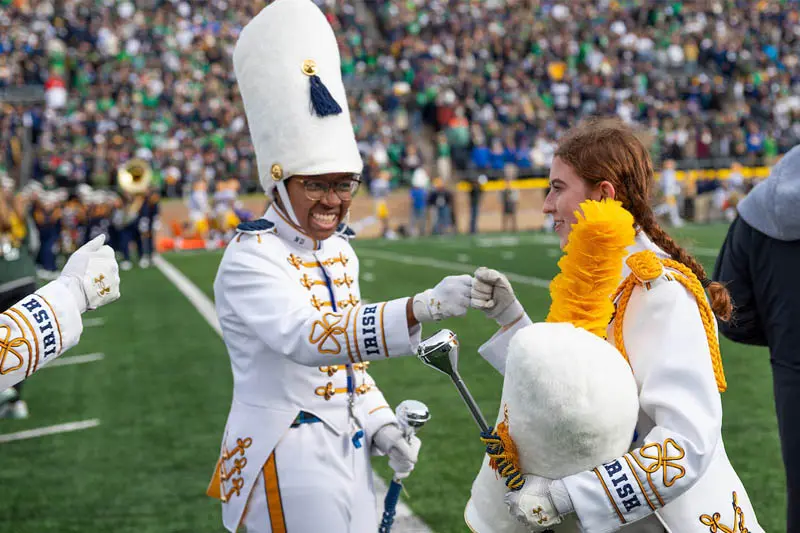 Assistant drum major Savannah Carr gives a fist bump to another band member on the Notre Dame football field.