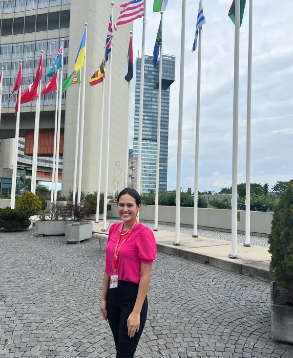 Elizabeth Gonzalez and stands in front of the flags at the United Nations in Vienna.