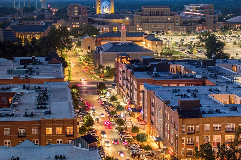 Eddy Street at dusk, shot from above with the Hesburgh Library and the Word of Life Mural—more commonly known as Touchdown Jesus—lit up in the background.