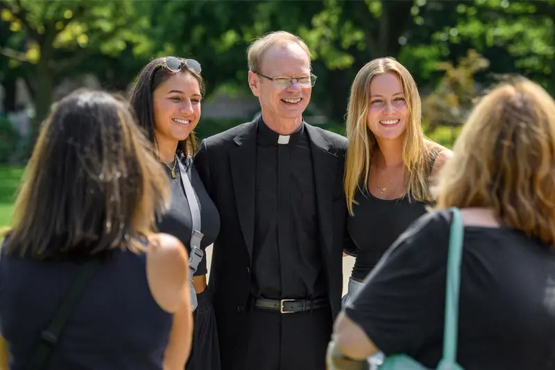 A photo of Fr. Dowd standing in a crowd of female students