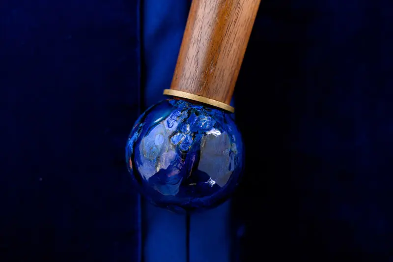 A shiny blue marble ball at the bottom of the wooden handle of the mace.