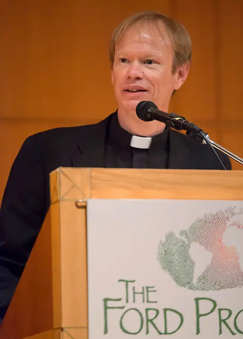 Father Bob Dowd stands at a podium talking.