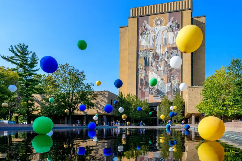 Blue and Gold ballons floating over the reflecting pool in front of the Hesburgh Library.