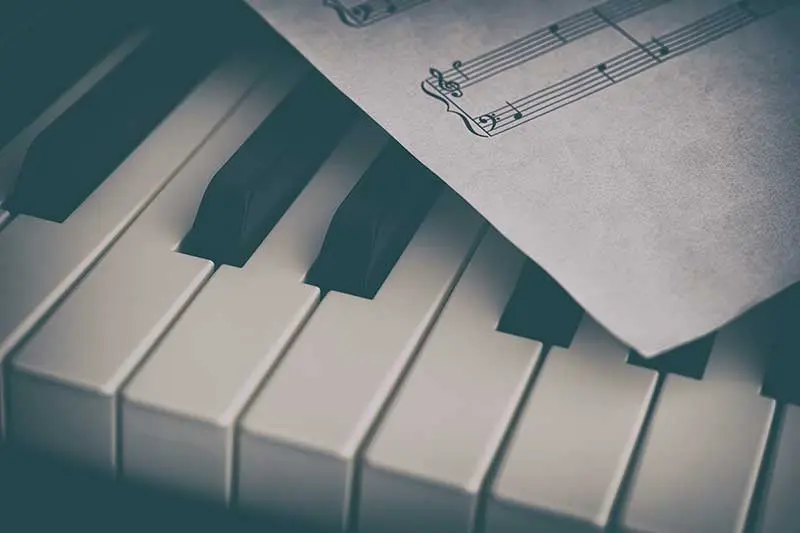 Piano keys with sheet music laid on top of them.