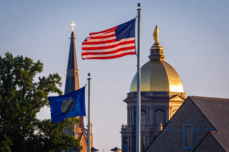 The Notre Dame and U.S. flags fly in front of the campus skyline