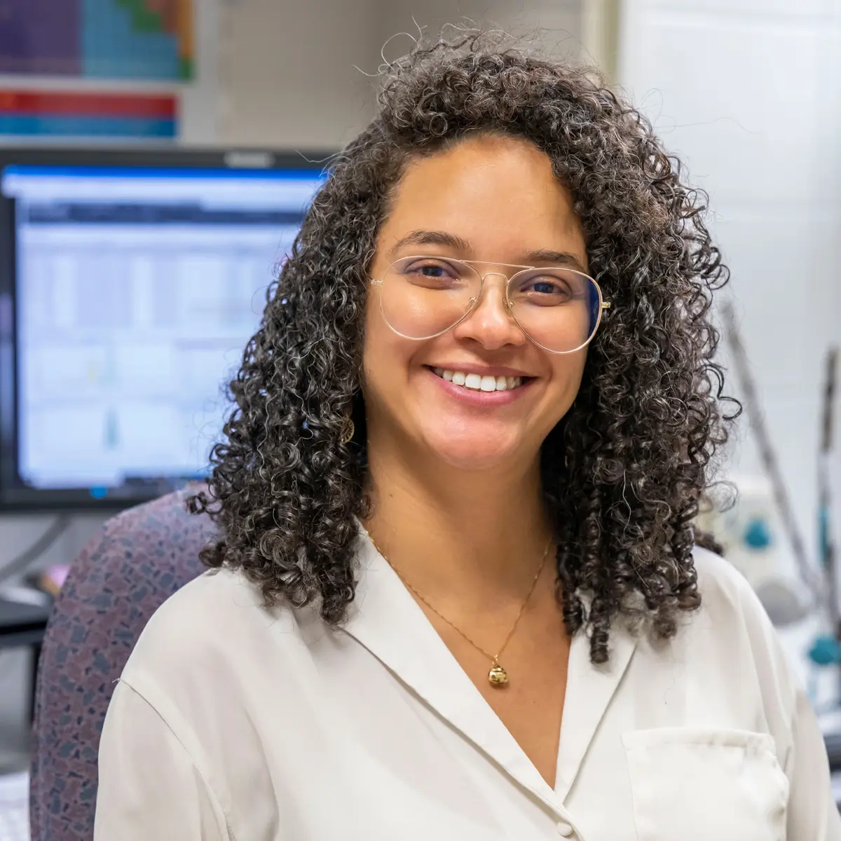 A portrait of Daniele Miranda wearing glasses and a white lab coat.