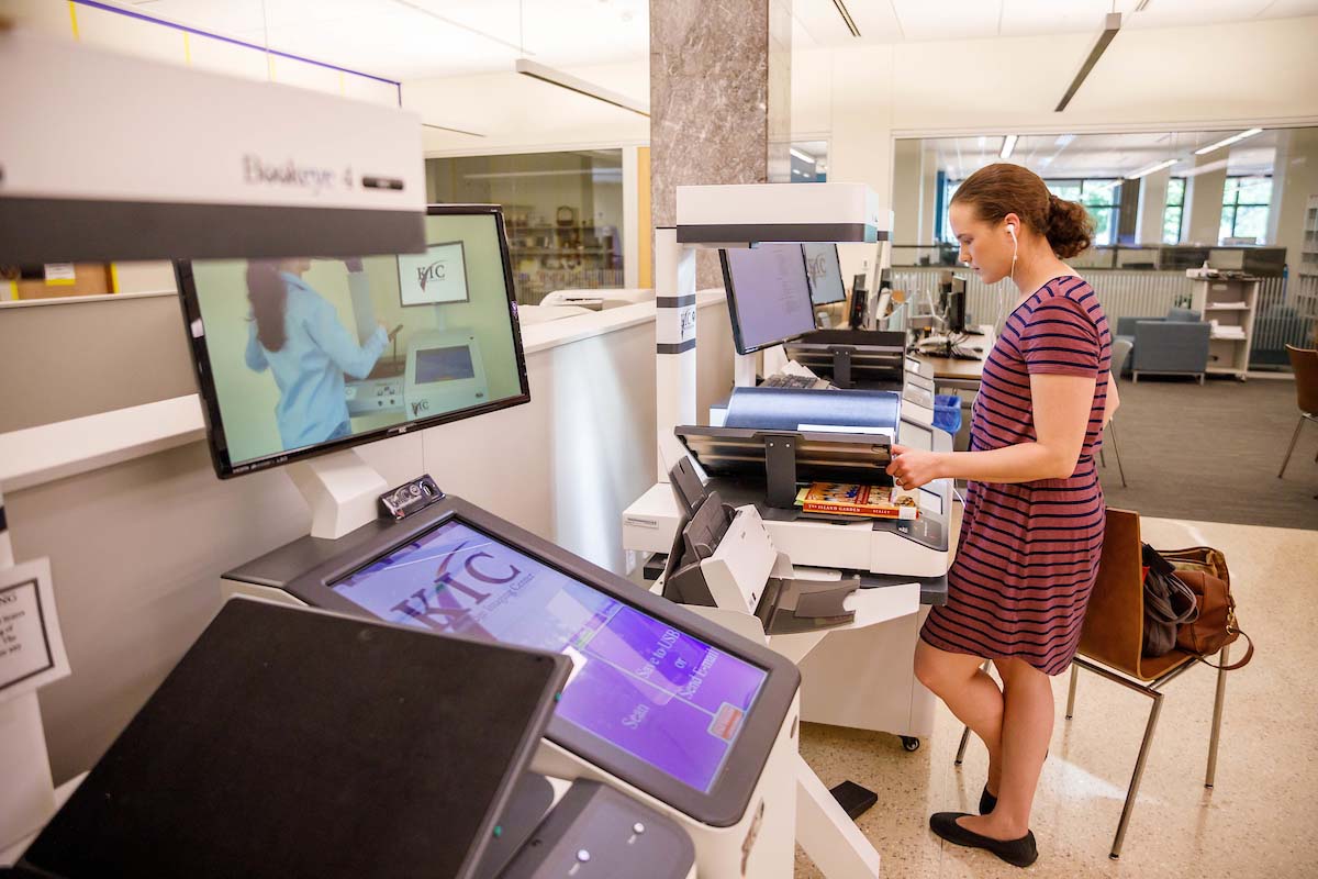 A women scans a textbook at a printing station.