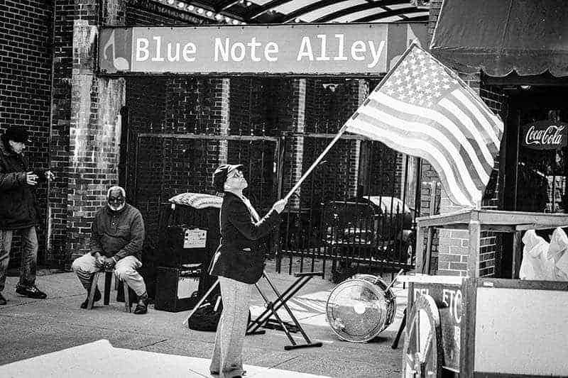 A woman holding an American flag in front of Blue Note Alley.