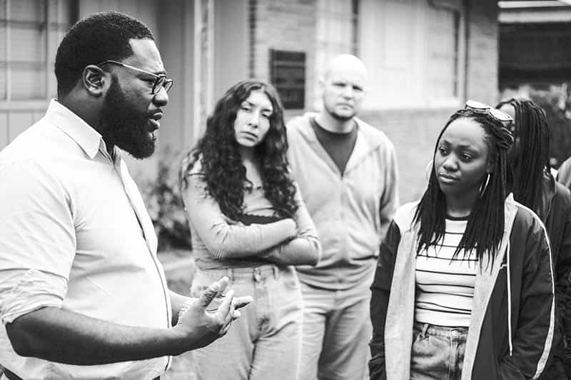 A man speaks to students outside.