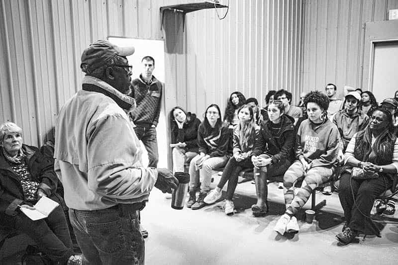 A man speaks to a group of students in a room.