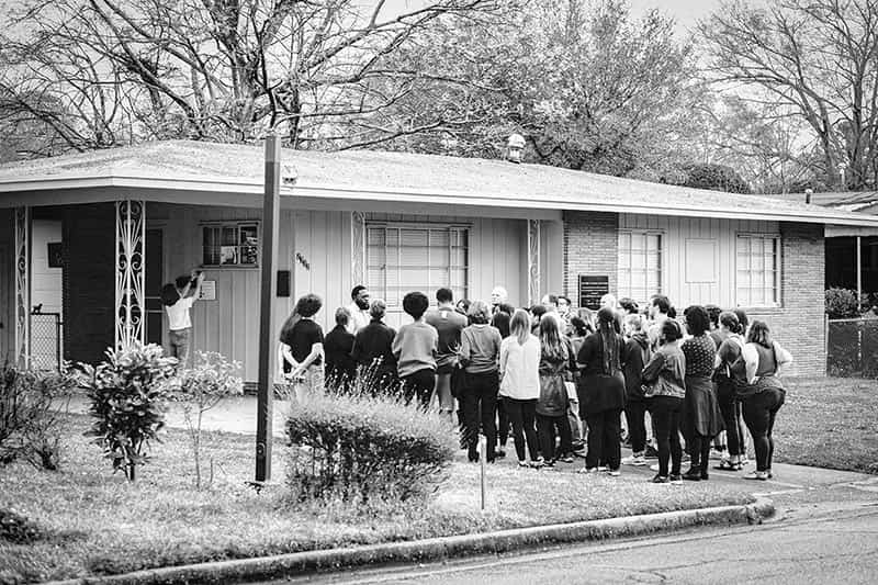 A group of students stand in the driveway of Medgar Ever's home.