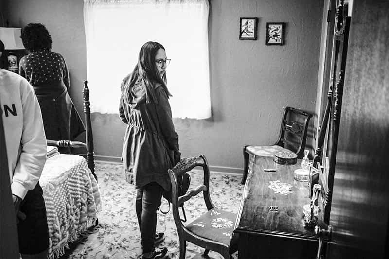 A student looks at a desk and mirror in a room of Medgar Ever's home.