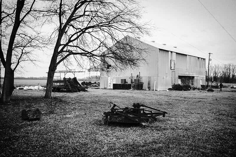 An open field with a barn in the background and farm equipment in the foreground.