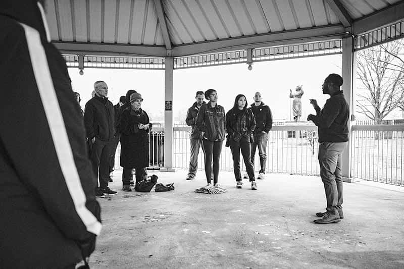 A man talking to a group of students with the Fannie Lou Hamer statue in the background.