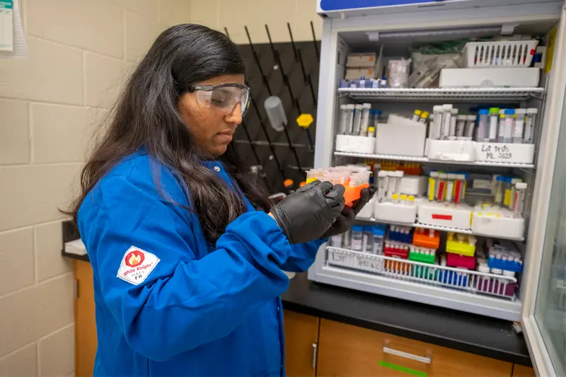 Graduate student Anita Amate removes fentanyl solutions stored in a refrigerator with other controlled substances for use in the analysis of street drugs.