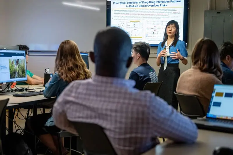 Professor Fanny Ye stands at the front of a classroom presenting on opioids.